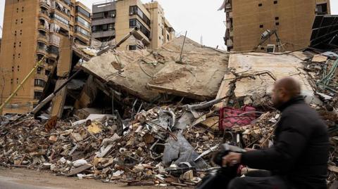 A motorcycle passes in front of buildings damaged after bombing in Beirut's Dahiyeh suburb 