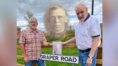 Gary and Geoff stand alongside a street sign "Draper Road" and hold a photo of William Draper