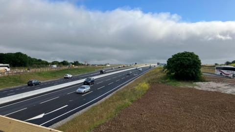 Several cars driving along part of the A30 in Cornwall with fields either side of the carriageways