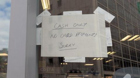 A sign on a Co-op shop reading "Cash only, no card payments, sorry"