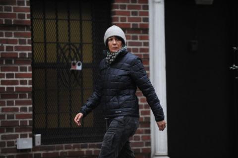 Ghislaine Maxwell wearing a gray hat and black jacket and jeans walks in front of a brick building looking to the side after leaving her East 65th Street townhouse in Manhattan on 04 January 2015