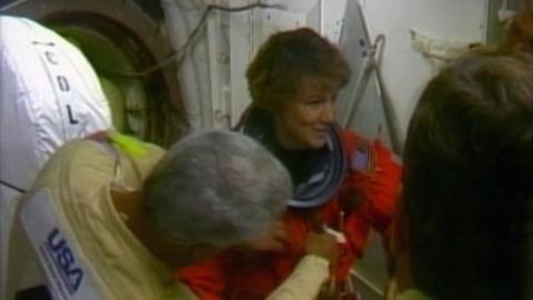 Eileen Collins is helped into an orange space suit