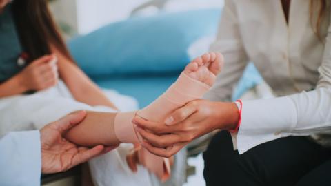 child gets checked over as health professional examines a foot in a bandage
