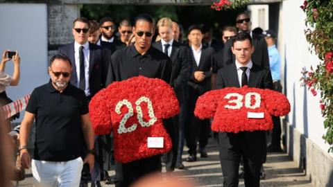 Liverpool players Virgil van Dijk (C) and Andrew Robertson (R) carry floral tributes