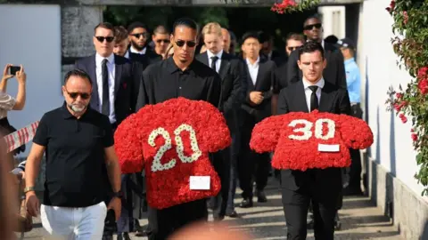 Liverpool players Virgil van Dijk (C) and Andrew Robertson (R) carry floral tributes