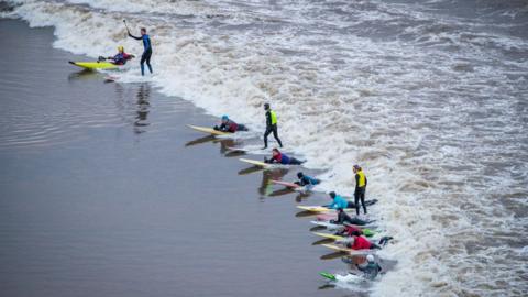 Surfers riding the river Severn bore