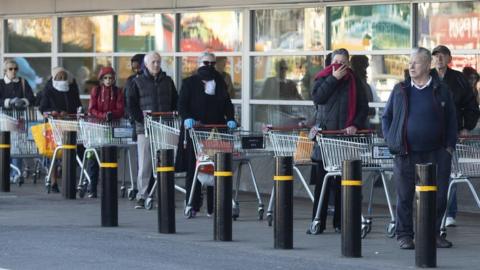 Shoppers queuing outside a supermarket