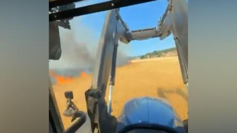 Tractor drives past burning field.