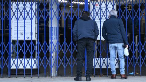 Two men looking through shutters at a Tube station during strike action in November 2022.