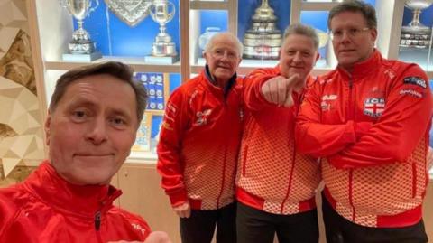 Douglas McGlynn points at the camera alongside his dad, Andy and Martin Gregory far left and Stuart Brand on the right, who make up the England team who will compete at the World Seniors Curling Championships.