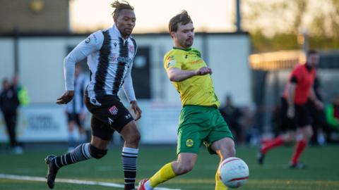 Caernarfon's Noah Edwards holds off the challenge of Flint's Jean Louis Akpa Akpro