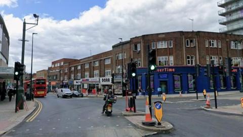 A screengrab of a street on Google street view. A junction with a row of shops in the background, with cars, motorbikes and buses on the streets. A blue casino sits on the corner.