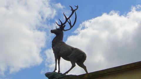 A statue of a bronze stag on a roof