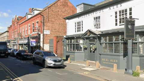 Grey and white painted doubled fronted pub on a busy town centre street.