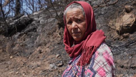 Mounia Hamiss standing near burnt trees