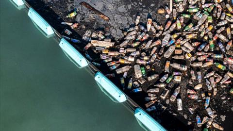 Plastic bottles piled up behind the Ocean Clean-up's interceptor barrier in Kingston Harbour, Jamaica