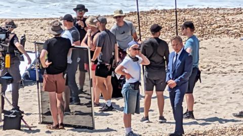 Film crews on a beach in Dorset near the sea on a sunny day
