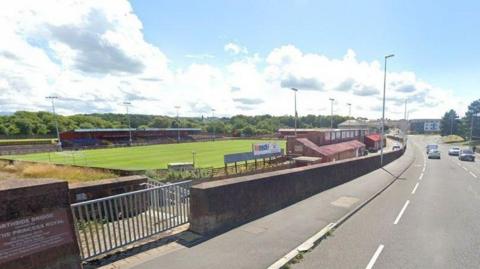 A general view of Borough Park in Workington. The stadium has two stands at either side of the pitch and is just off a main road. The ends are open and there are four floodlight pylons along each touchline.