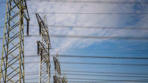 Electricity pylons stretching across a cloudy sky - stock photo