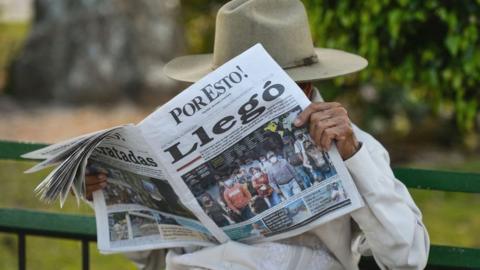 A man reads 'Por Esto!' (English: 'That's Why!'), a daily Mexican newspaper that covers the Mexican states of Yucatán, Campeche, and Quintana Roo, December 2021