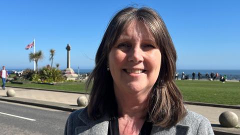 Councillor Karen Allison stands in front of Seaham seafront on a sunny day.