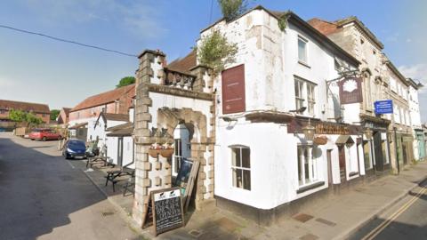 The Mason Arms' exterior- a white building with a red board and signage