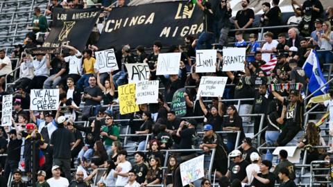 LAFC fans hold homemade signs protesting against US president Donald Trump's deportation policies