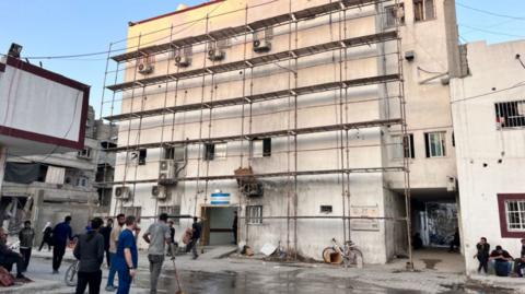 The Kamal Adwan hospital in Beit Lahya in the northern Gaza Strip on October 31, 2024. The building has scaffolding on it and people gathering outside 