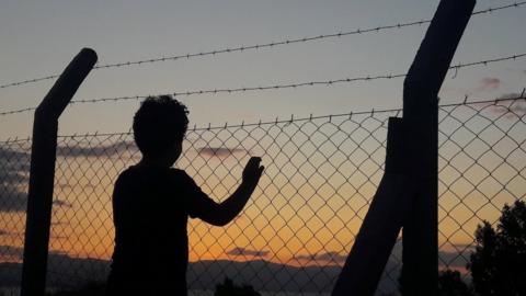 Man Standing By Fence Against Sky During Sunset - stock photo