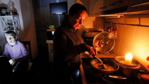 Woman cooking on primus stove in Kyiv during power cut, 20 Oct 22