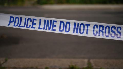 Blue and white police tape reads 'police line do not cross'