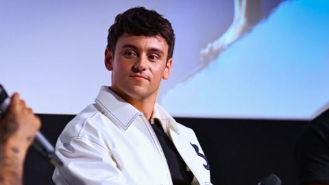 Tom Daley wearing a white jacket at a Q&A screening for the documentary, Tom Daley: 1.6 Seconds
