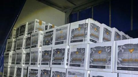 Boxes of gin stacked up to four high in the back of a HGV. The white boxes are printed with a grey and orange label, which reads "toffee apple".