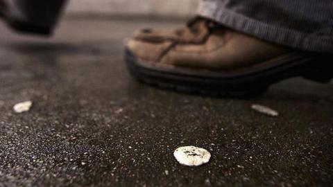 Chewing gum on street with man's shoes in background.
