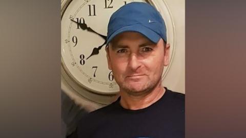 A man with a blue cap and black top