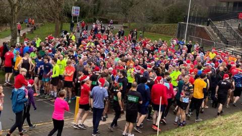 Crowds of runners, many in Santa hats, gather outside.