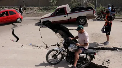 Motorobike and car stuck in cracked road 