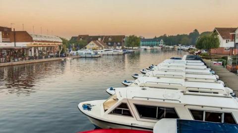 A row of moored boats opposite properties situated next to the water