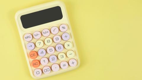 A picture of a pale yellow calculator with a mix of pale pink, purple, yellow and orange buttons. The calculator is on a brighter yellow background
