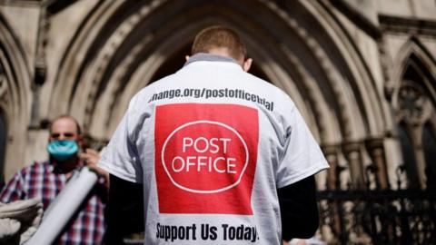 The back of a man walking into a court, with a T-shirt that asks people to support victims of the Horizon scandal