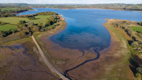 An image showing Chew Valley Lake which has dried out from the hot weather.