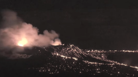 Night shot of Kilauea volcano erupting, clouds of smoke coming out from the top of the crater