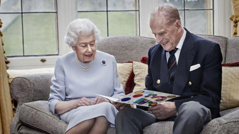 Queen and Prince Philip looking at a card from the Duke and Duchess of Cambridge's children