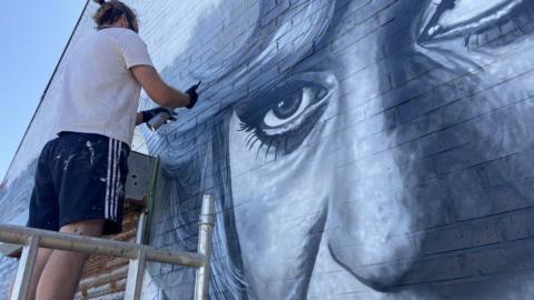 Artist, Brezaux, working on his mural tribute to Paul O'Grady