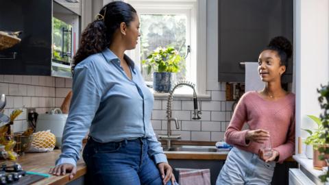 Mum chatting to tennage girl in the kitchen