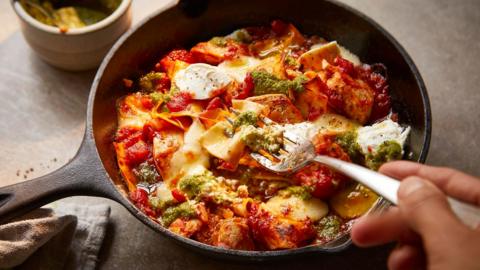 Chicken lasagna in a pot, with someone taking a scoop out of it with a fork