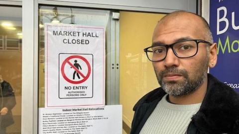 Trader Mikesh Varma looks forlorn stood next to a no entry sign on the indoor section of Bury Market.