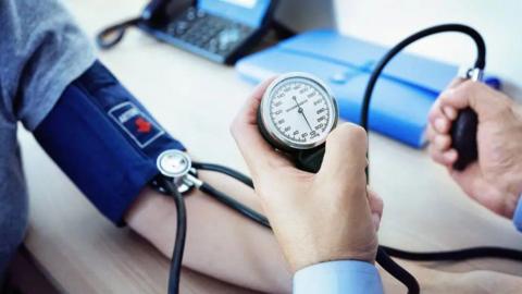 A doctor uses a manual blood pressure monitor to measure a patient's blood pressure during a routine medical check-up.