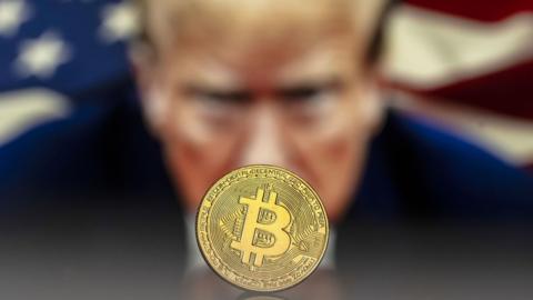 An illustration shows a Bitcoin mockup in front of an image of US President Donald Trump.