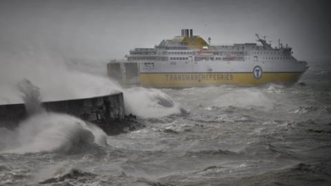 A white and yellow ferry on rough water leaving a harbour.